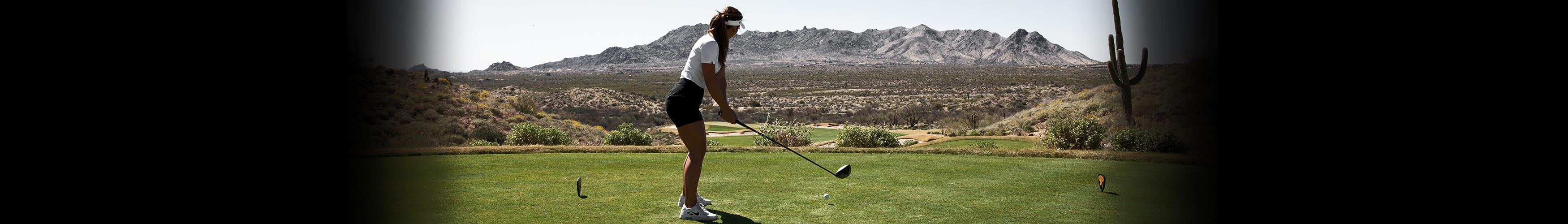 Women golfer setting up to hit a drive